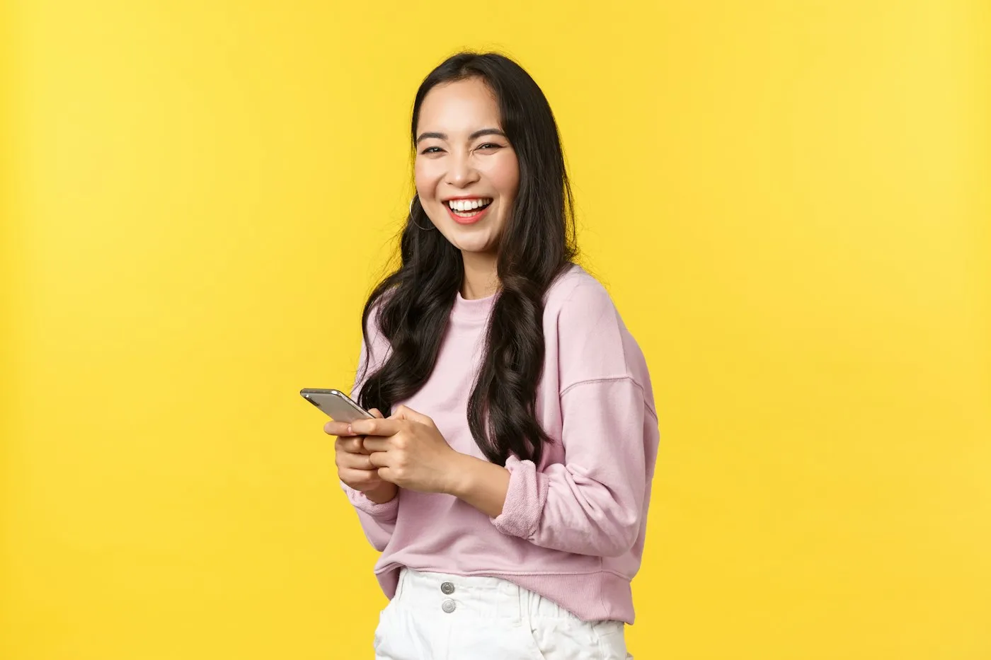 Cliente sorrindo com o celular na mão, em fundo amarelo
